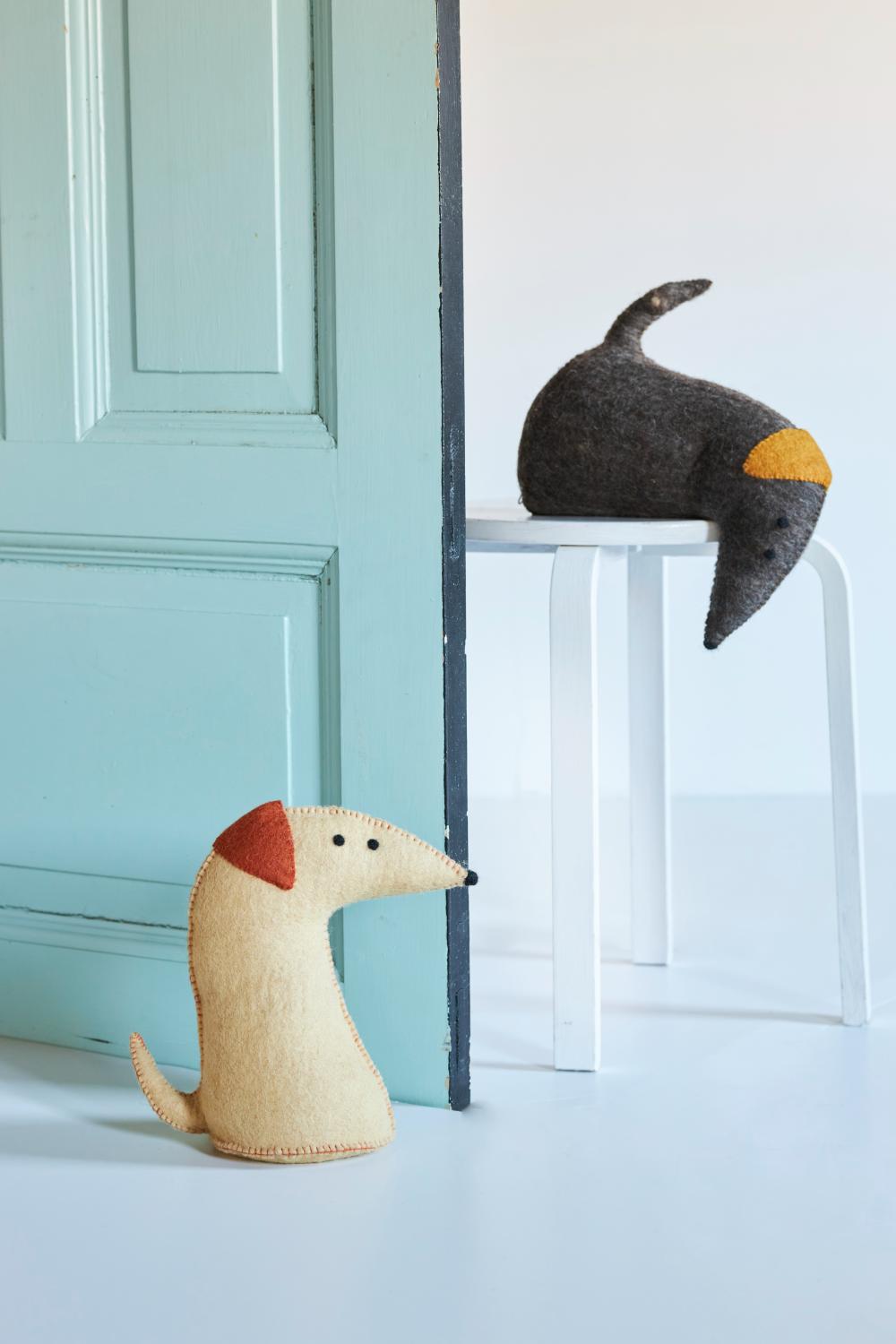 Cale-porte teckel Dog crème Aveva placé devant une porte
