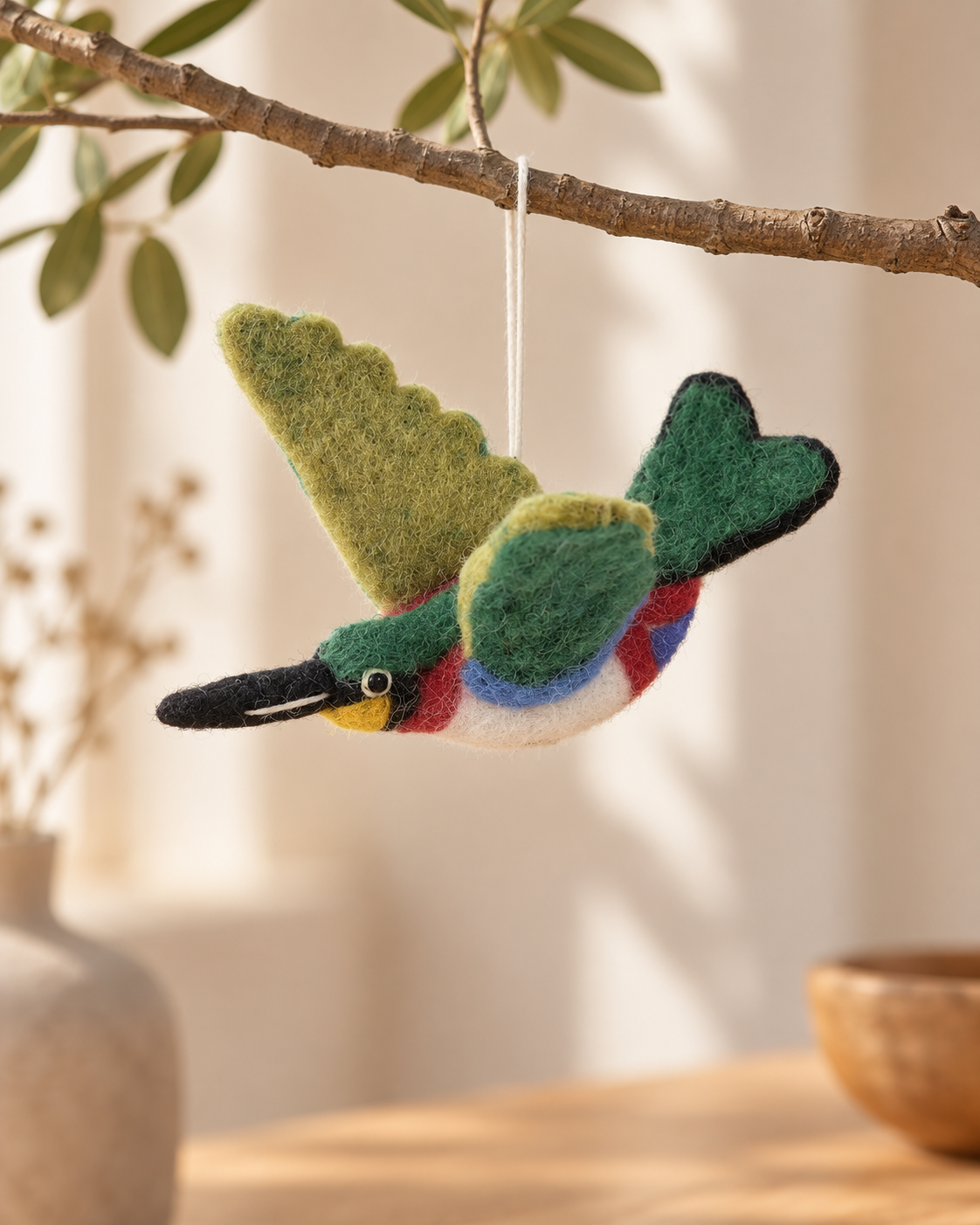 Oiseau vert mousse Aveva en laine suspendu à une branche, mise en situation reconstituée par IA