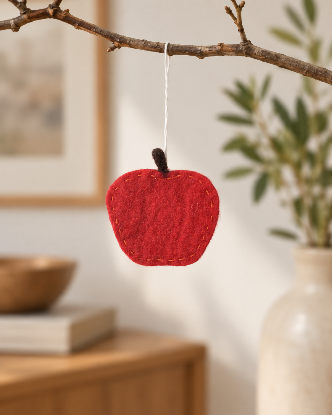 Pomme rouge Aveva en laine suspendue à une branche, mise en situation reconstituée