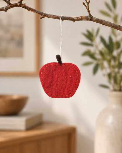 Pomme rouge Aveva en laine suspendue à une branche, mise en situation reconstituée