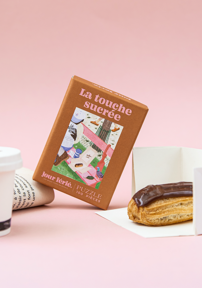 Boîte La touche sucrée Jour Férié près d’un éclair au chocolat et d’un journal