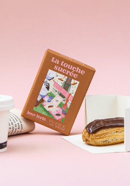 Boîte La touche sucrée Jour Férié près d’un éclair au chocolat et d’un journal