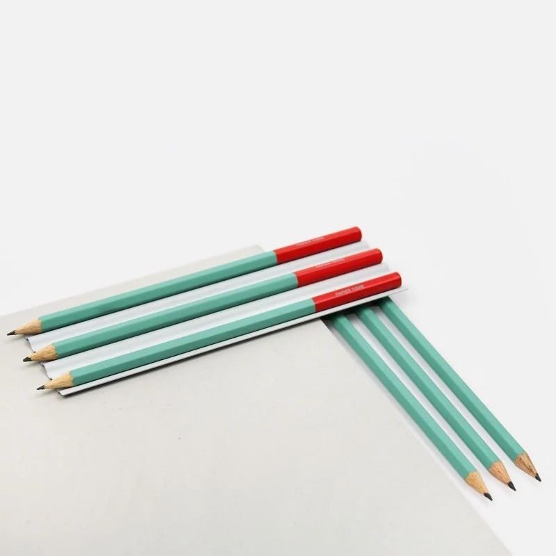 Crayons vert et brique Papier Tigre disposés sur un bloc blanc