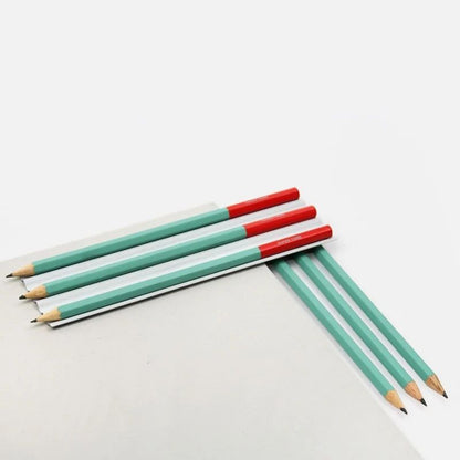 Crayons vert et brique Papier Tigre disposés sur un bloc blanc