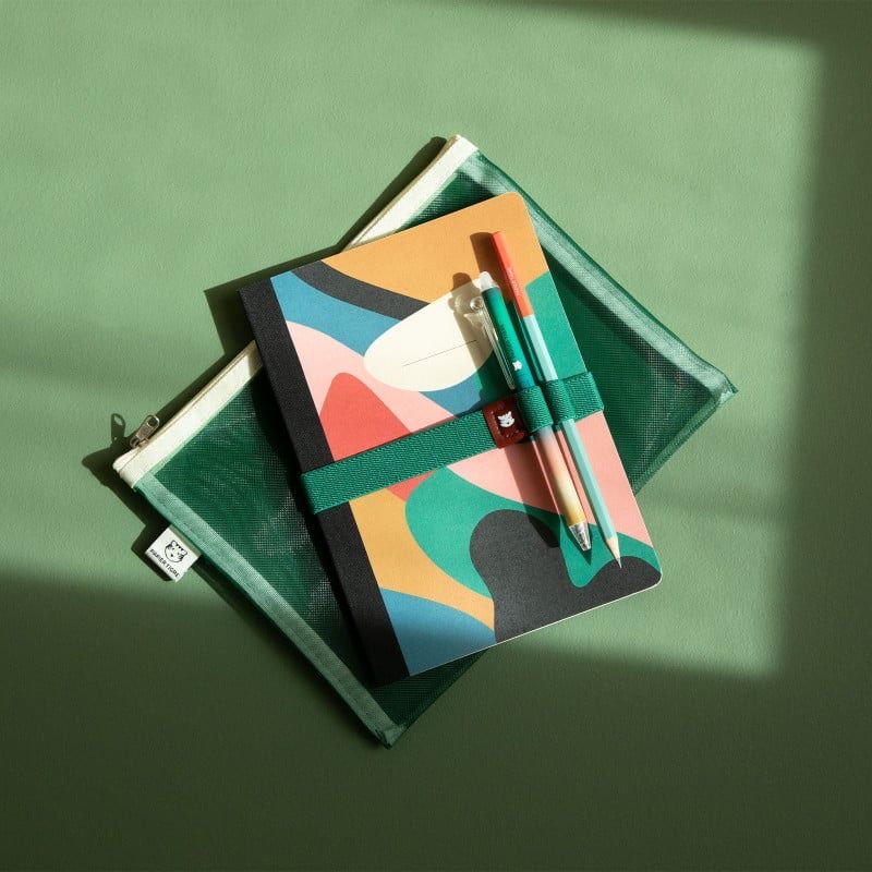 Crayon vert et brique Papier Tigre mis en scène avec un carnet et une trousse