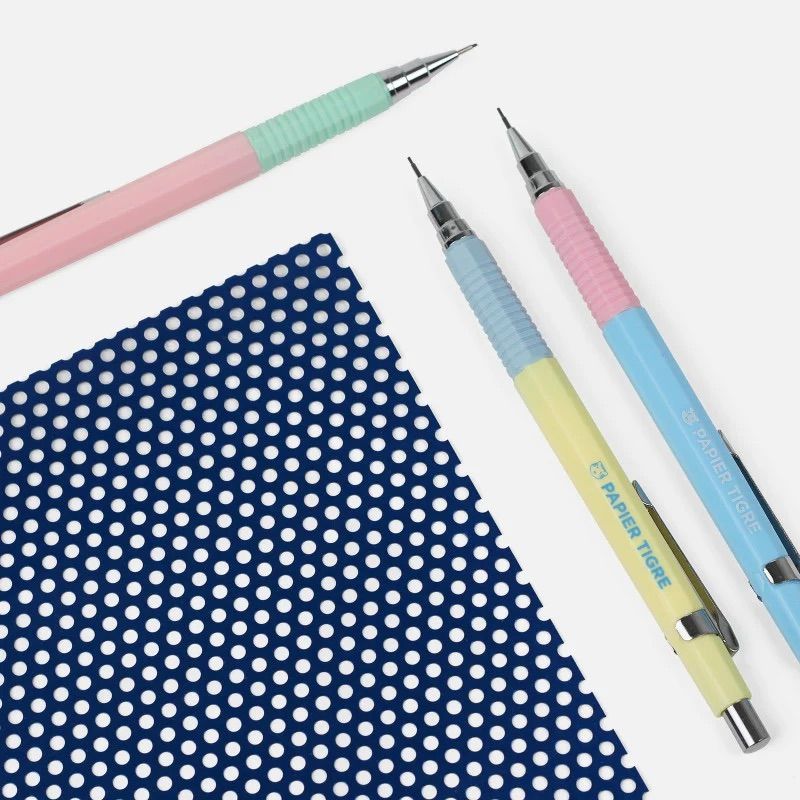 Trois critériums bicolores Papier Tigre disposés sur un carnet