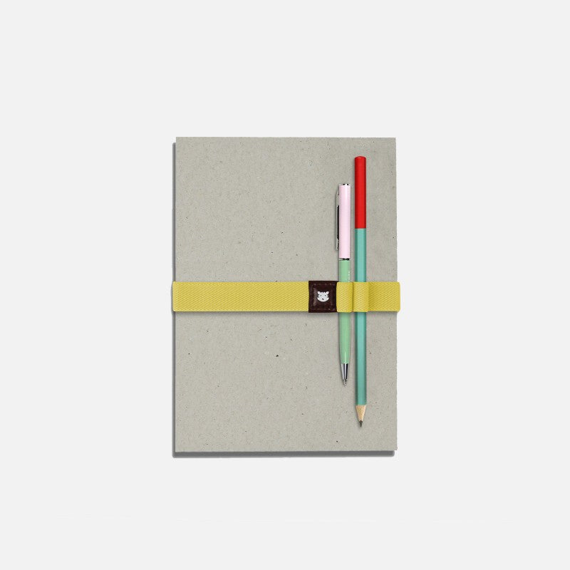 Le Voyageur jaune Papier Tigre tenant deux stylos sur un carnet
